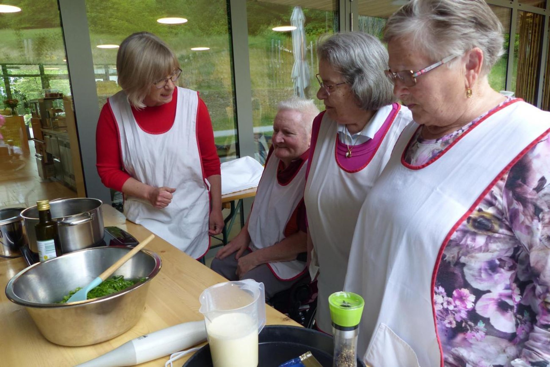 Eine Gruppe von Frauen in Schürzen bereitet gemeinsam Essen zu.