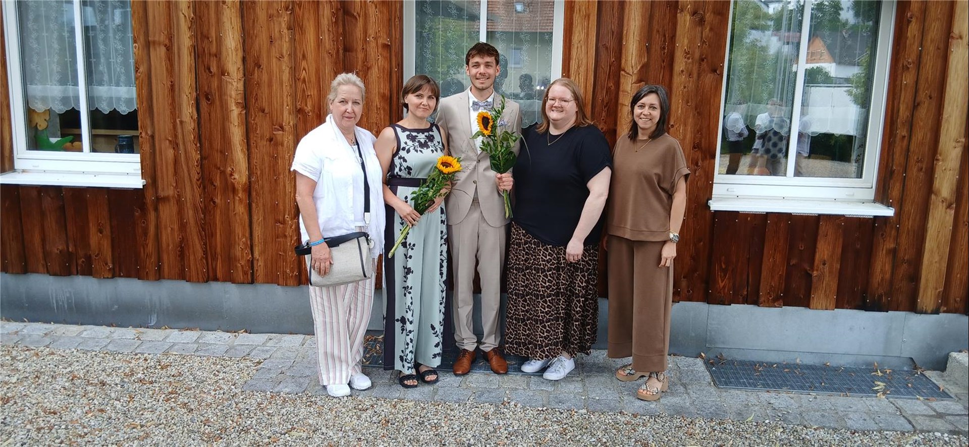 Vier Personen stehen vor einer Wand aus Holz